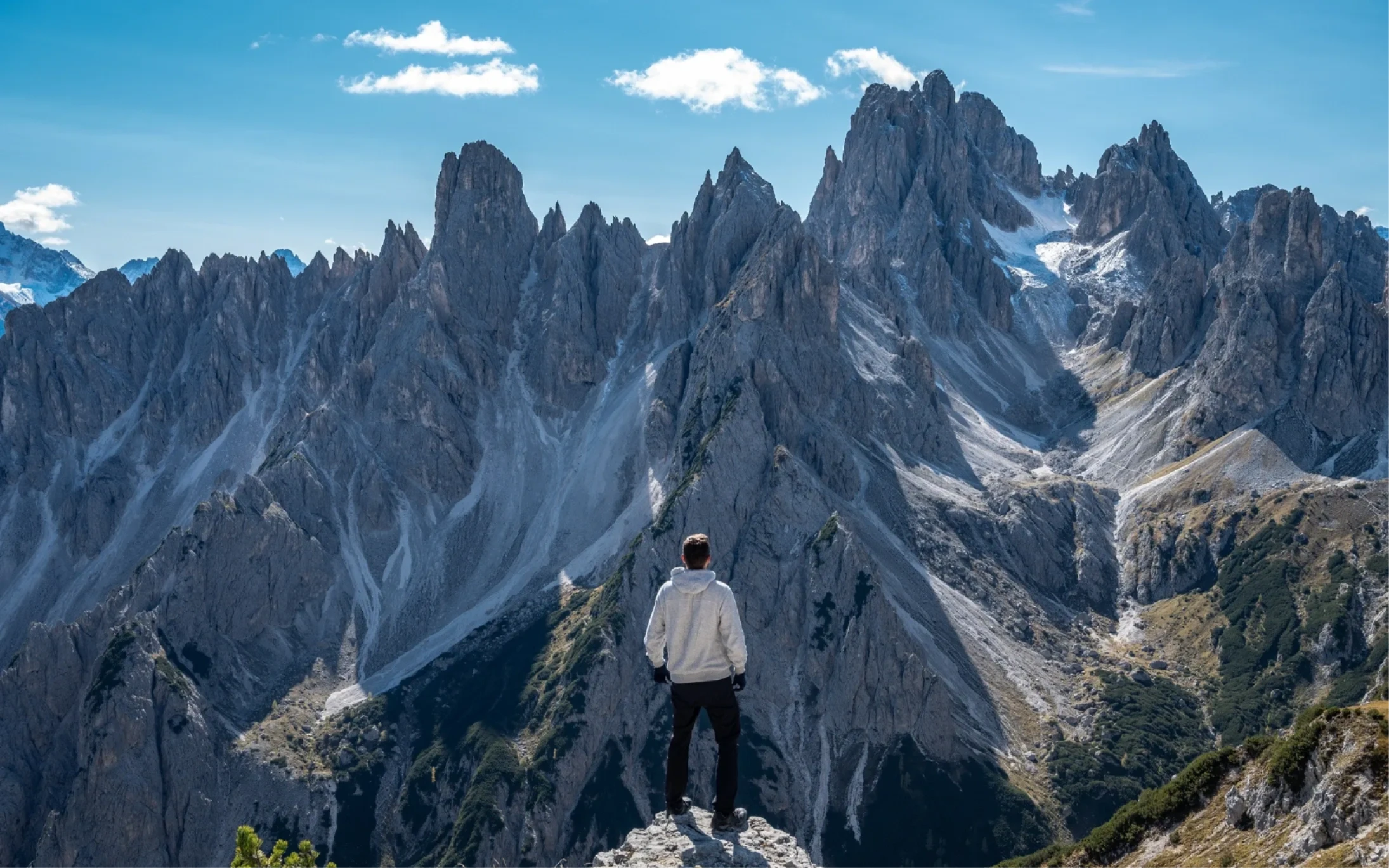 Hiker overlooking a turquoise alpine lake and snow-capped peaks